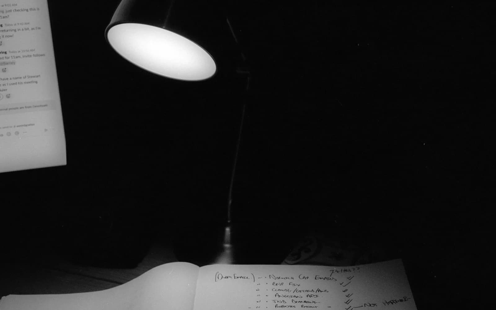 A lit desk lamp beside an open notebook and pen